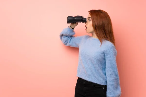 Pembe Bir Arka Plan Uzaktan Dürbünle Bakarak Genç Kızıl Saçlı — Stok fotoğraf