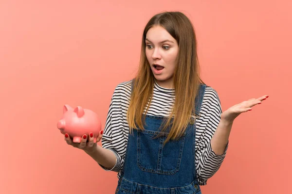 Young Woman Overalls Pink Wall Surprised While Holding Piggybank — Stock Photo, Image