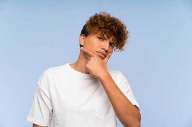 Beyaz gömlekli Afro-Amerikan genç adam ayakta duruyor ve bir fikir düşünüyor.