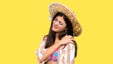 Yaz tatilinde genç kız izole sarı arka plan üzerinde bir çaba yapmış olması için omuz ağrısı muzdarip