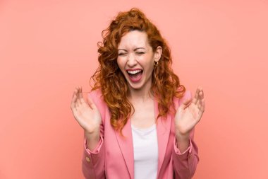 Izole pembe duvar gülerek üzerinde takım elbiseli Redhead kadın