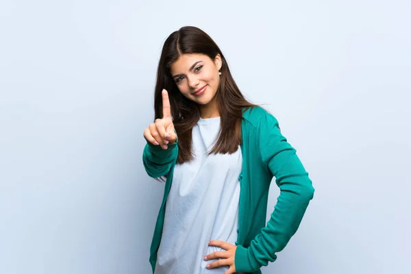 Teenager Mädchen Über Blauer Wand Zeigt Und Hebt Einen Finger — Stockfoto