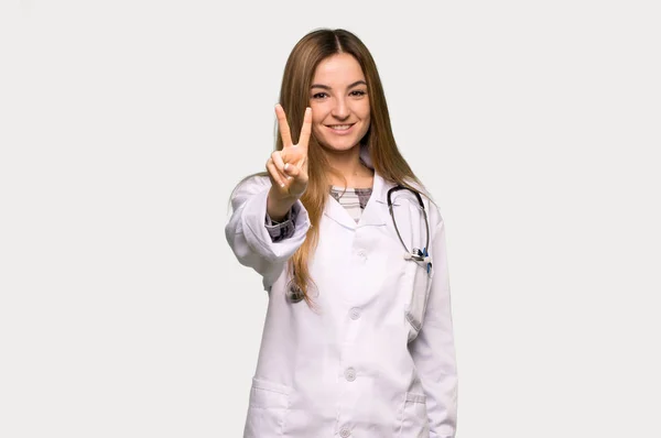 Joven Doctora Sonriendo Mostrando Signo Victoria Sobre Fondo Gris Aislado — Foto de Stock