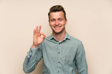 Parmakları ile ok işareti gösteren izole duvar üzerinde Sarışın yakışıklı adam