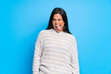 Kazaklı genç Kolombiyalı kız kameraya dil gösteriyor. Komik bir bakışı var.