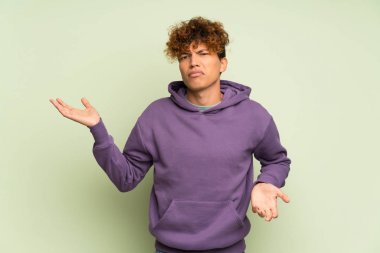 Bir şeyi anlamadığı için mutsuz olan yalnız yeşil duvarın üzerindeki genç Afrikalı Amerikalı adam.