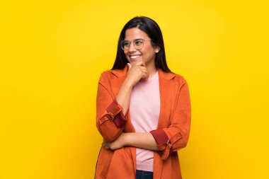 Sarı duvarın arkasında eli çenesinde genç bir Kolombiyalı kız var.