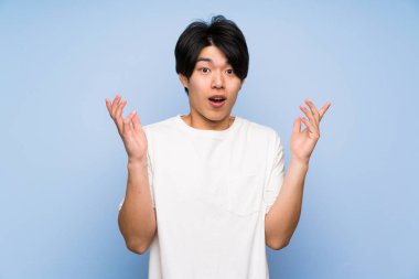 Sürpriz yüz ifadesi ile izole mavi arka plan Asyalı adam