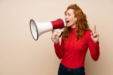Bir megafon ile bağıran boğazlı kazak ile Redhead kadın