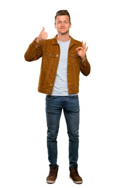 Sarışın yakışıklı adam ok işareti ve başparmak kadar jest gösteren