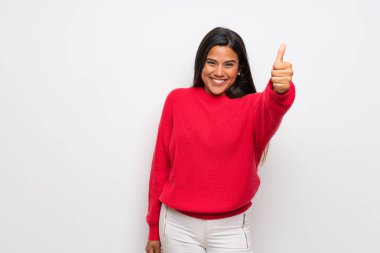 Kırmızı kazaklı genç Kolombiyalı kız başparmağı havada çünkü iyi bir şey oldu.