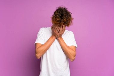 Genç Afro-Amerikalı adam, yorgun ve hasta bir ifadeyle izole edilmiş mor duvarın üzerinde.