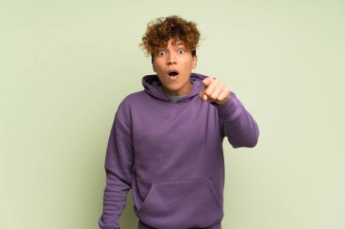 Tecrit edilmiş yeşil duvarın üstünde genç bir Afro-Amerikan erkeği şaşırdı ve ön tarafı işaret etti.