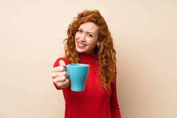 Redhead woman with turtleneck sweater holding hot cup of coffee