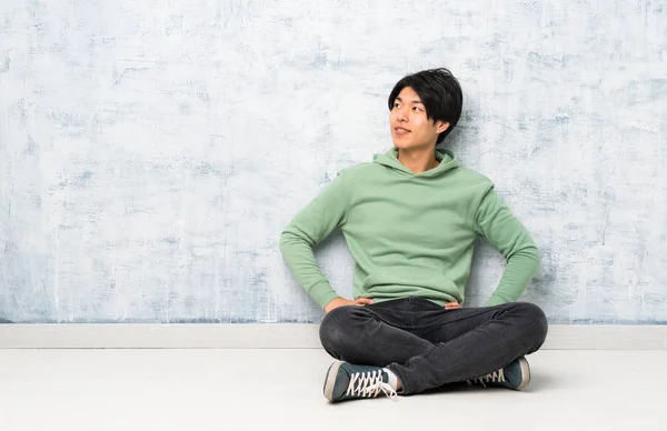 Asiatischer Mann Sitzt Auf Dem Boden Und Posiert Mit Den — Stockfoto