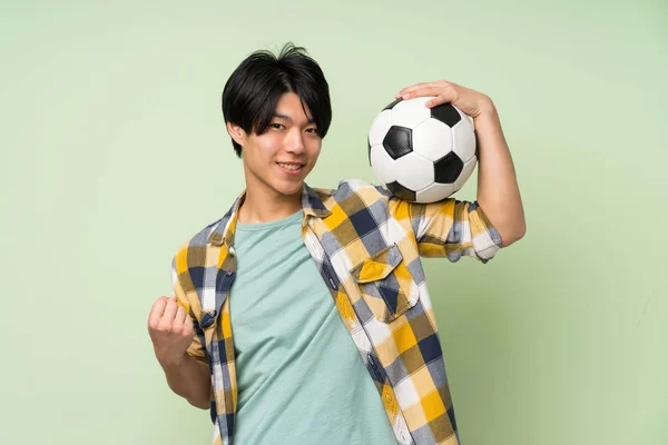 Asiatisk Mann Isolert Grønn Vegg Som Holder Fotball – stockfoto