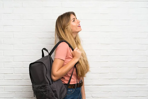 Jovem Loira Sobre Parede Tijolo Branco Com Mochila — Fotografia de Stock