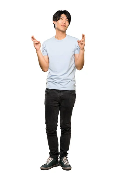 青いシャツを着たアジア人男性のフルレングスショットで 指が交差し 孤立した白い背景の上に最高のものを願っています — ストック写真