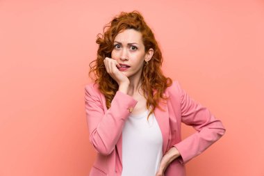 Izole pembe duvar sinirli ve korkmuş üzerinde takım elbiseli Redhead kadın
