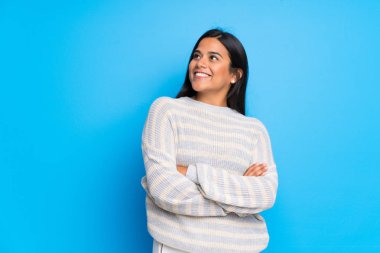 Süveterli genç Kolombiyalı kız gülümserken yukarı bakıyor