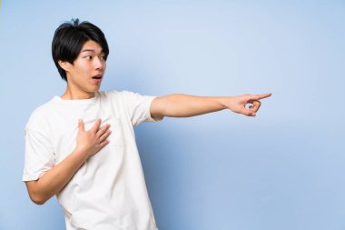 Izole mavi arka plan yan parmak işaret Asyalı adam