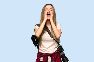 Genç fotoğrafçı kadın bağırıyor ve mavi arka planda bir şey duyuruyor.