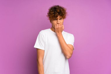 İzole edilmiş mor duvarın üzerinde kuşkuları olan genç Afrikalı Amerikalı bir adam.