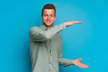 Bir reklam eklemek için copyspace tutan izole mavi duvar üzerinde Blonde adam