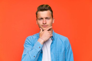 Sarışın yakışıklı adam ayakta ve bir fikir düşünce izole duvarın üzerinden