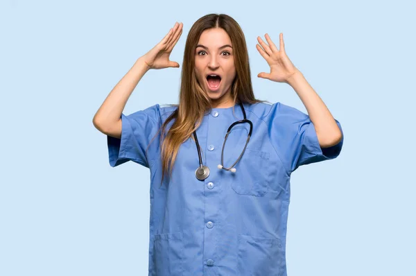 Junge Krankenschwester Mit Überraschung Und Schockiertem Gesichtsausdruck Auf Isoliertem Blauen — Stockfoto