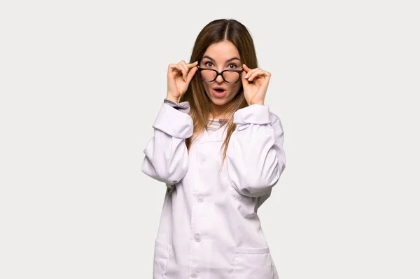 Giovane Donna Medico Con Gli Occhiali Sorpreso Sfondo Grigio Isolato — Foto Stock