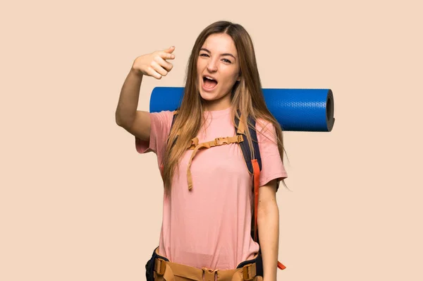 Young backpacker woman frustrated by a bad situation and pointing to the front on isolated yellow background