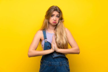 Sarı önlüklü genç sarışın kadın yalvarıyor.