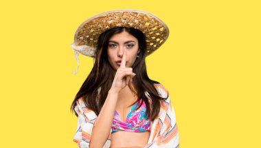 Yaz tatilinde genç kız izole sarı arka plan üzerinde ağızparmak koyarak sessizlik jest bir işareti gösteren