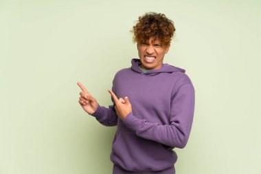 Genç Afro-Amerikan adam yeşil duvarın ötesinde korkmuş ve kenarı işaret ediyor.