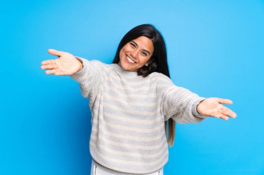 Süveterli genç Kolombiyalı kız sunar ve davet eder.