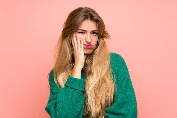 Jovem Mulher Loira Com Suéter Verde Sobre Parede Rosa Infeliz — Fotografia de Stock