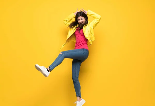 Nastolatek dziewczyna przeskakując na białym tle ściana żółty — Zdjęcie stockowe
