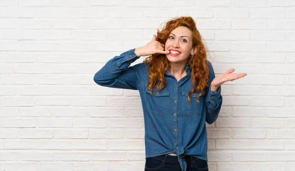 Redhead Žena Bílou Cihlovou Stěnou Která Dělá Telefonní Gesto Pochybuje — Stock fotografie