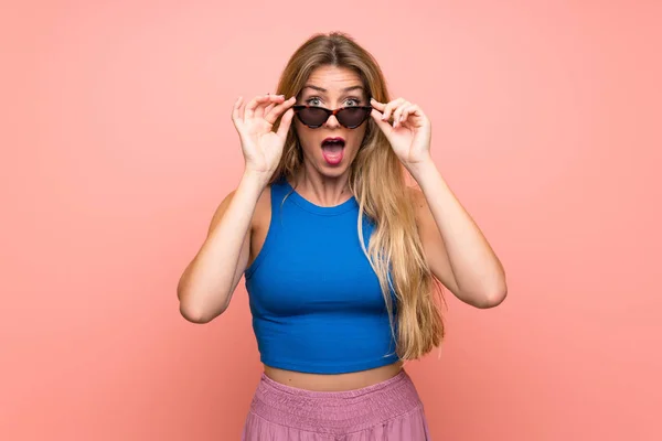 Joven Rubia Sobre Fondo Rosa Aislado Con Gafas Sorprendida —  Fotos de Stock