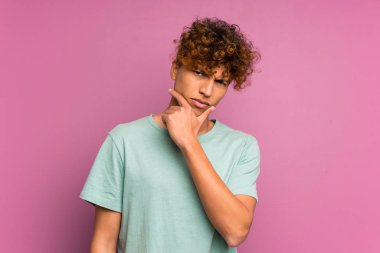 Genç Afro-Amerikan bir adam mor duvarın üzerinde duruyor ve bir fikir düşünüyor.