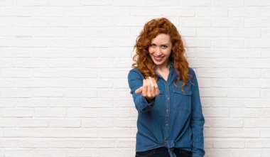 Beyaz tuğla duvar üzerinde Redhead kadın el ile gelmeye davet ediyor. Geldiğin için mutluyum.