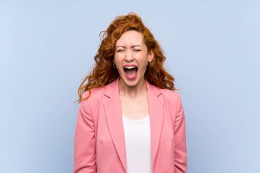 Izole mavi duvar üzerinde takım elbiseli Redhead kadın ağzı geniş açık ön bağırarak