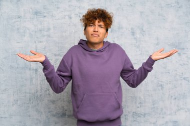 Genç Afro-Amerikan bir adam grunge duvarını aştı. Kafası karışık yüz ifadesiyle ilgili şüpheleri var.