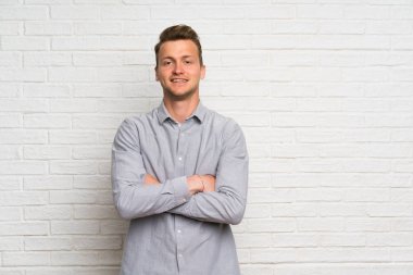 Kollarını ön konumda geçti tutmak beyaz tuğla duvar üzerinde Blonde adam