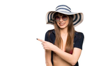 Bikinili genç bir kadın, izole edilmiş beyaz arka planda parmağını yana doğru gösteriyor.