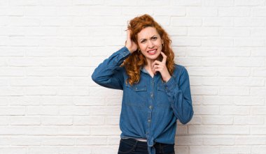 Beyaz tuğla duvar üzerinde Redhead kadın şüpheleri olan