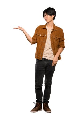 İzole beyaz arka plan üzerinde şüpheler ile copyspace tutan kahverengi ceket ile Asyalı bir adam tam uzunlukta bir çekim