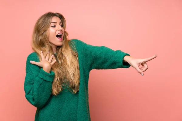 Young Blonde Woman Green Sweater Pink Wall Pointing Finger Side — 스톡 사진