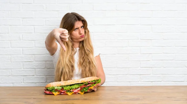 Молода Блондинка Тримає Великий Бутерброд Роблячи Поганий Сигнал — стокове фото